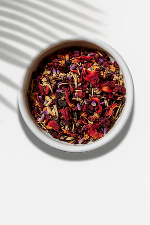 Assorted dried herbs and flowers in a white bowl on a light background