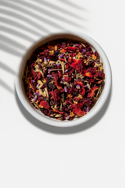 Assorted dried herbs and flowers in a white bowl on a light background